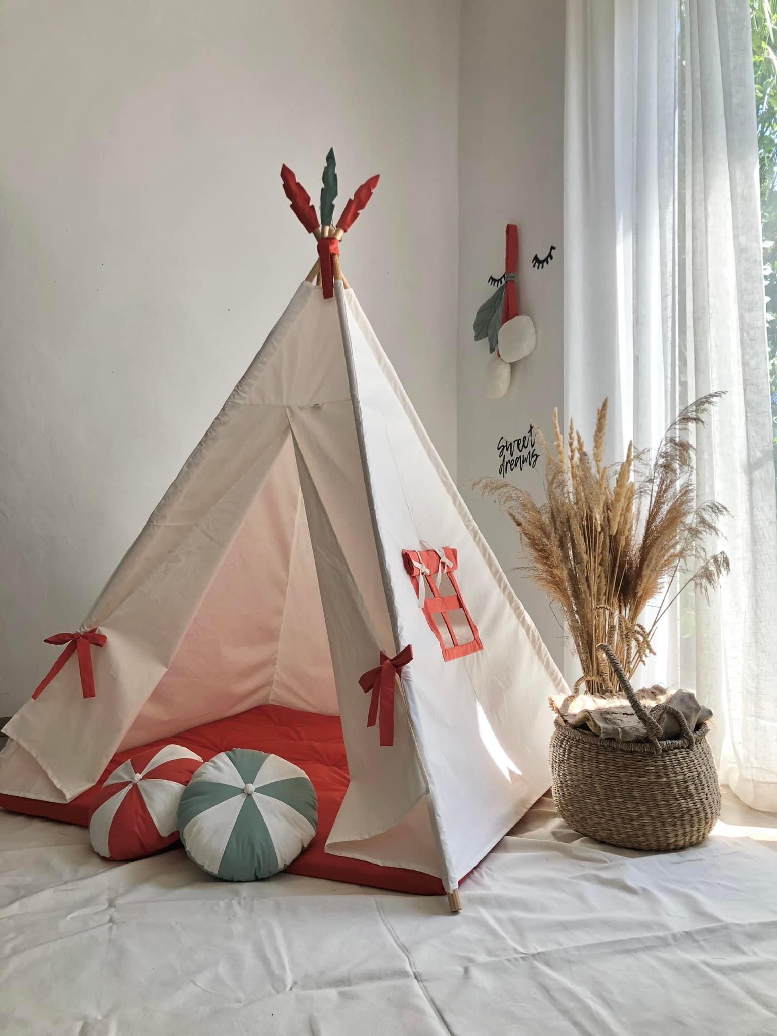 White tent with a fire-colored mattress and round pillows